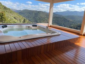 una bañera de hidromasaje en una terraza con montañas al fondo en Pousada R.N.C. Nosso Paraíso, en Teresópolis