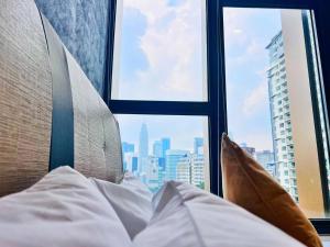 a bed with a view of a city from a window at KLCC View Grand Studio Suites ceylonz in Kuala Lumpur