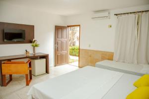 a bedroom with two beds and a desk and a window at Jeri Village Hotel in Jericoacoara