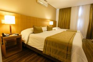 a hotel room with a large bed and a telephone at Casablanca Center Hotel in Petrópolis