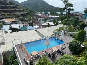 a swimming pool with chairs and umbrellas on a building at Uphill Cottage in Phi Phi Islands