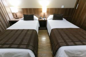 two beds in a small room with a desk at Casablanca Center Hotel in Petrópolis
