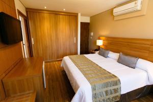 a hotel room with a bed and a flat screen tv at Casablanca Center Hotel in Petrópolis