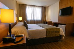 a hotel room with a bed and a telephone at Casablanca Center Hotel in Petrópolis