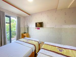 um quarto com duas camas e uma televisão na parede em Khách sạn Triều Dâng em Liên Trì (4)