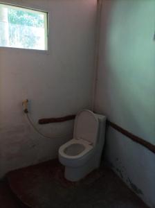 a small bathroom with a toilet and a window at Lawang Inn in Bukit Lawang