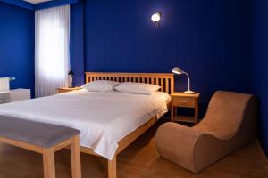 um quarto azul com uma cama e uma cadeira em Artament Prishtina em Pristina