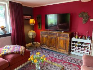 a living room with a television on a red wall at Happy Teapot Apartment in Malsfeld