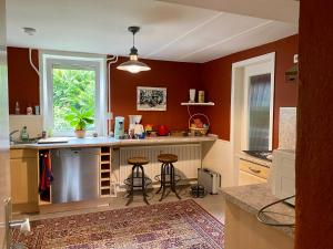 una cucina con pareti arancioni e bancone con sgabelli di Happy Teapot Apartment a Malsfeld
