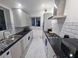 una cucina bianca con lavandino e piano cottura di Spacious 5 bedroom House in South Norwood Croydon a Norwood
