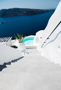 a white staircase leading up to a pool on a white house at By The Mill in Oia