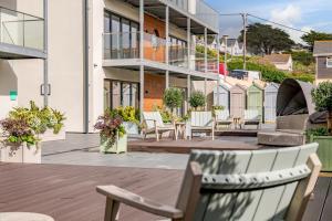 a balcony with chairs and tables on a building at 1 Rockham - Luxury Apartment at Byron Woolacombe, only 4 minute walk to Woolacombe Beach! in Woolacombe