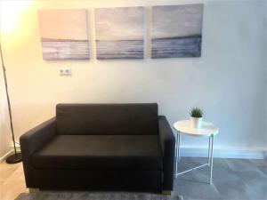 ein Wohnzimmer mit einem Sofa und zwei Gemälden an der Wand in der Unterkunft Möblierte 3 Zimmer Apartment - Mit Smart TV, Wlan und kostenfreie Parkplätze in Schloß Holte-Stukenbrock