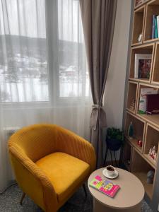 una silla amarilla y una mesa en una habitación con ventana en Modern Mountain EXCLUSIVE en Kolašin