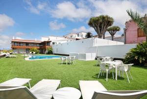 a yard with white tables and chairs and a pool at Linaje del Pago Castellana in Tacoronte