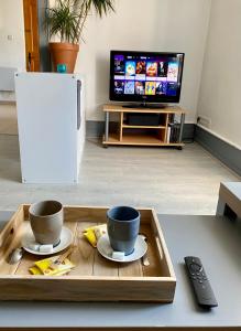 bandeja con 2 tazas en una mesa con TV en Grand f2 au calme centre de village, en Dampierre-les-Bois