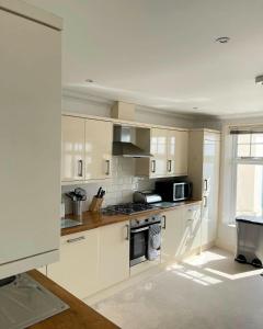 a kitchen with white cabinets and a stove top oven at Shore Thing Beachfront Apartment Ramsgate - Sleeps 4 in Ramsgate