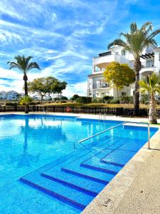 una gran piscina con palmeras y un edificio en Hacienda Riquelme Charming Apartment, en Sucina