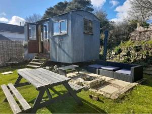 a blue tiny house with a picnic table and a bench at Treguth Glamping Unique Experience - Themed Huts in Saint Day