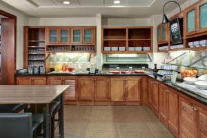 a large kitchen with wooden cabinets and a table at Tulsa South Medical Hotel & Suites in Tulsa