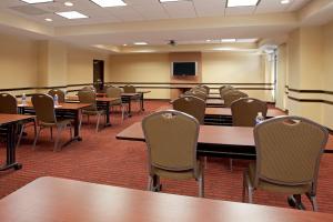 a conference room with tables and chairs and a tv at Tulsa South Medical Hotel & Suites in Tulsa