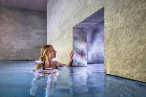 a woman in a swimming pool with a mirror at Superior Hotel Alpenhof in Flachau