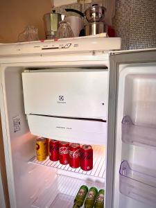 an open refrigerator with cans of soda in it at Residencial Bem-te-vi in Jericoacoara