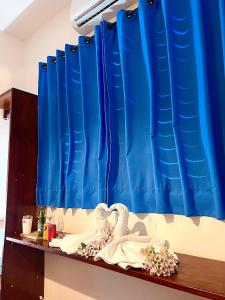 a shelf with blue curtains and two swans at Residencial Bem-te-vi in Jericoacoara