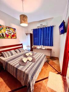 a bedroom with a bed and a window with blue curtains at Residencial Bem-te-vi in Jericoacoara
