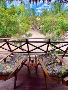 a balcony with two benches and a table and trees at Residencial Bem-te-vi in Jericoacoara