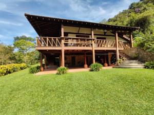 a large house with a deck on a green lawn at Sítio Sanandu - Conforto no Paraíso Ecológico de Macaé de Cima in Lumiar
