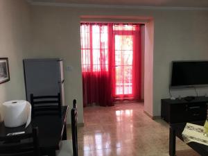 a living room with red curtains and a television at Domi Bed & Breakfast in Tirana