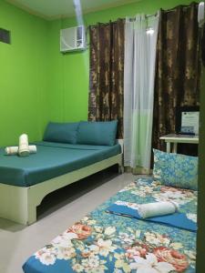 two beds in a room with green walls at Twin AP Homes in Boracay