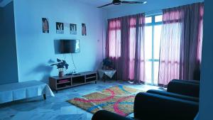 a living room with pink curtains and a tv at Cocobay Resort Cosy Apartment in Kampong Tanah Merah