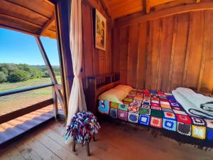 uma cama num quarto de madeira com uma janela em Pousada Ninho da Gralha em Turvo