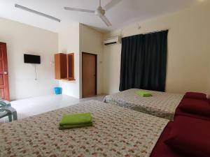 - une chambre avec 2 lits et des serviettes vertes dans l'établissement Nipahmas Chalet, à Île de Pangkor