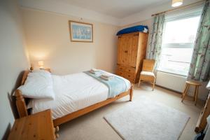 a bedroom with a bed and a chair and a window at Buckenham Cottage in Cromer