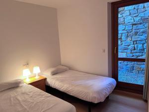 two twin beds in a room with a window at Pleta 214 in Soldeu