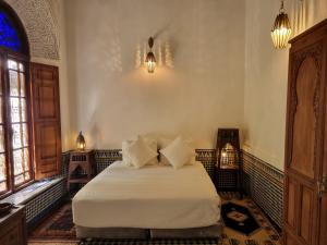 um quarto com uma cama branca e 2 almofadas em Riad Le Sucrier de Fès em Fez