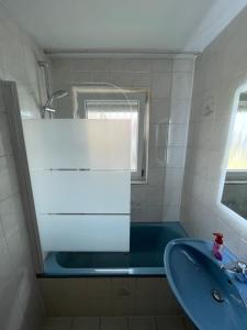 y baño con bañera azul y lavamanos. en Sonnige 3 Zimmer Wohnung mit schönem Balkon im Grünen, en Reutlingen
