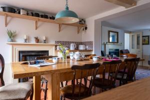 a dining room with a wooden table and a fireplace at Two Sides Cottage in Lymington
