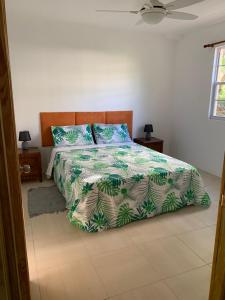 Schlafzimmer mit einem Bett mit einer grünen und weißen Bettdecke in der Unterkunft Kay Nou Apartments in Gros Islet
