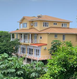 duży żółty budynek z drzewami przed nim w obiekcie Kay Nou Apartments w mieście Gros Islet