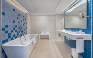 a bathroom with a tub and a sink and a mirror at Royal Azur Thalassa in Hammamet
