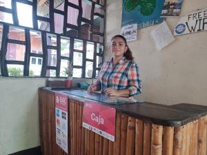 a woman is standing at a wooden counter at Hostal Así es mi Tierra in Balgue