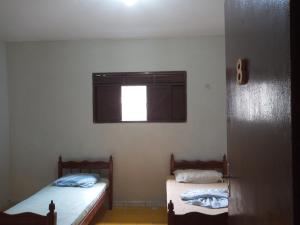 two beds in a small room with a window at Pousada Jardim do Éden in Parnamirim