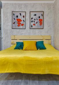 a yellow bed in a bedroom with two pictures on the wall at YourHouse на Розыбакиева Утепова недалеко от Меги in Almaty