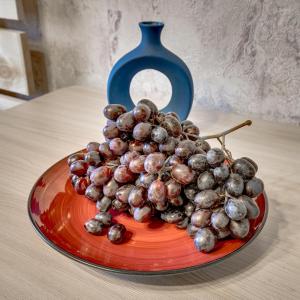a pile of grapes on a red plate on a table at YourHouse на Розыбакиева Утепова недалеко от Меги in Almaty
