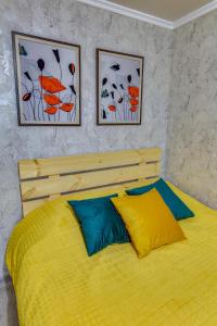a bedroom with a yellow bed with two pictures on the wall at YourHouse на Розыбакиева Утепова недалеко от Меги in Almaty