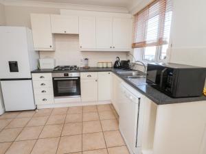 a kitchen with white cabinets and a sink and a microwave at 20 Southmead in Morpeth
